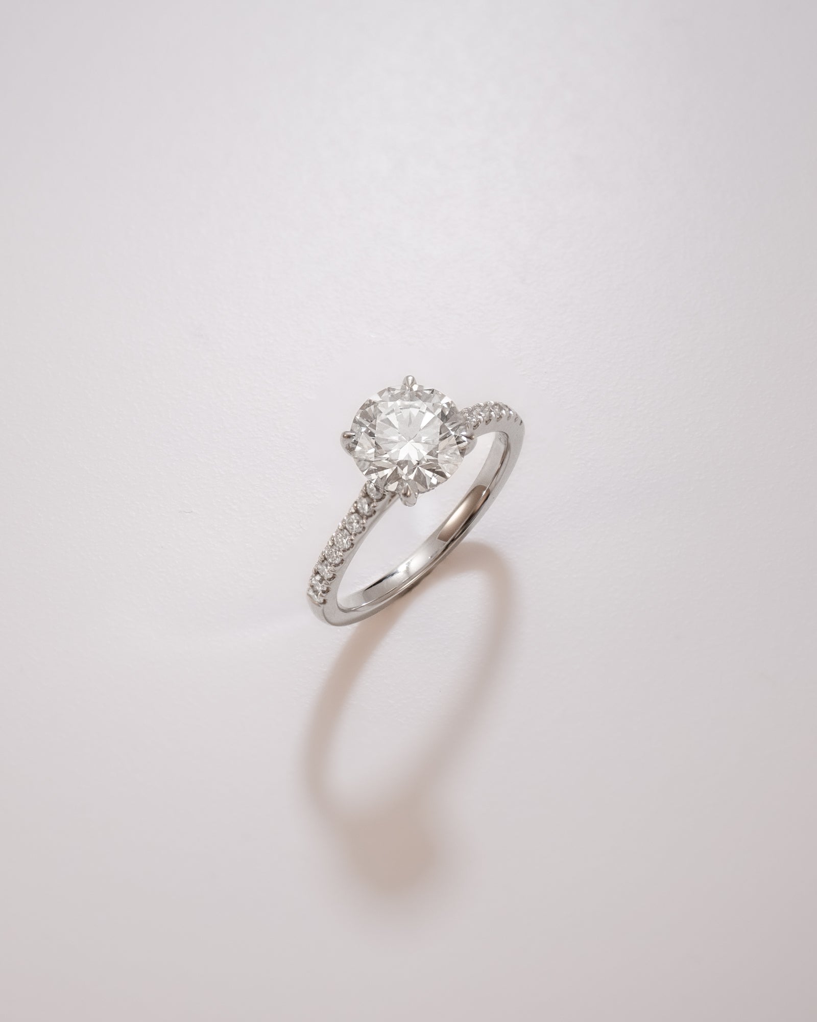 Round cut diamond pavé ring in cathedral setting in white gold on a soft neutral background – tinxx jewelry
