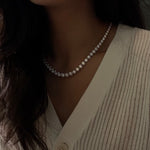 Close-up of a person wearing a 20ctw graduated diamond necklace with a neutral background
