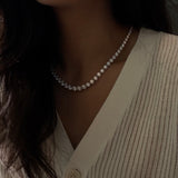 Close-up of a person wearing a 20ctw graduated diamond necklace with a neutral background