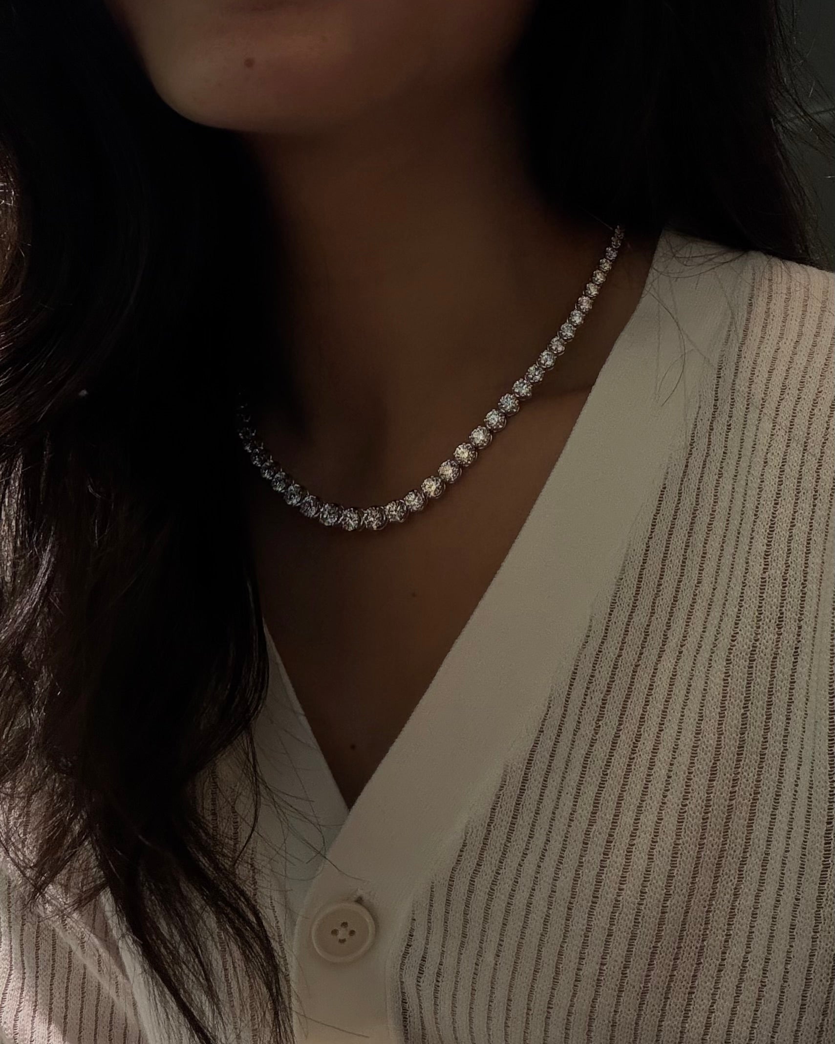 Close-up of a person wearing a 20ctw graduated diamond necklace with a neutral background
