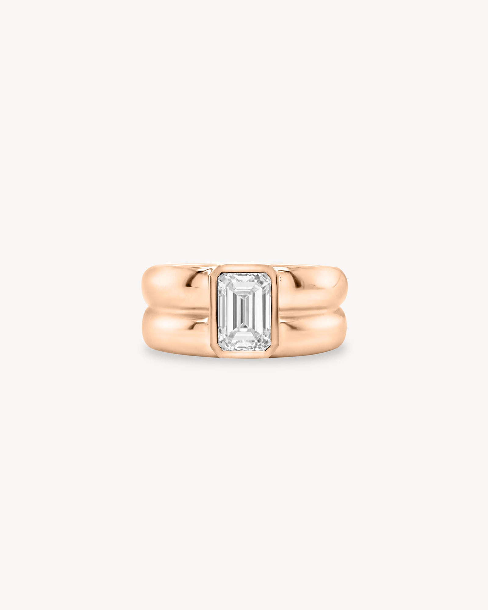 Emerald Cut diamond double gold band ring in 18K rose gold set against a white background