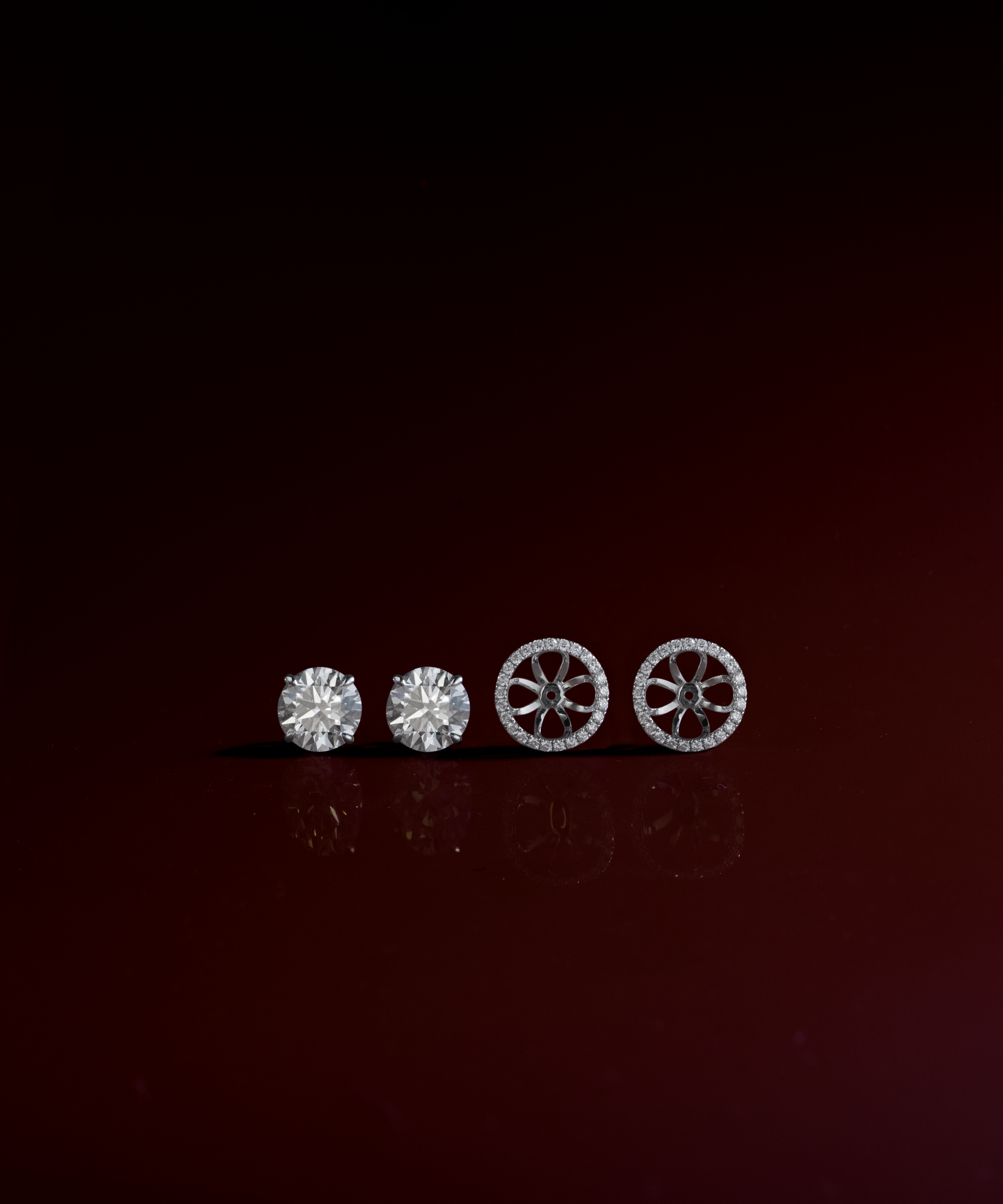 Round cut diamond stud earrings with removable halo jackets in white gold, styled on dark red – tinxx jewelry