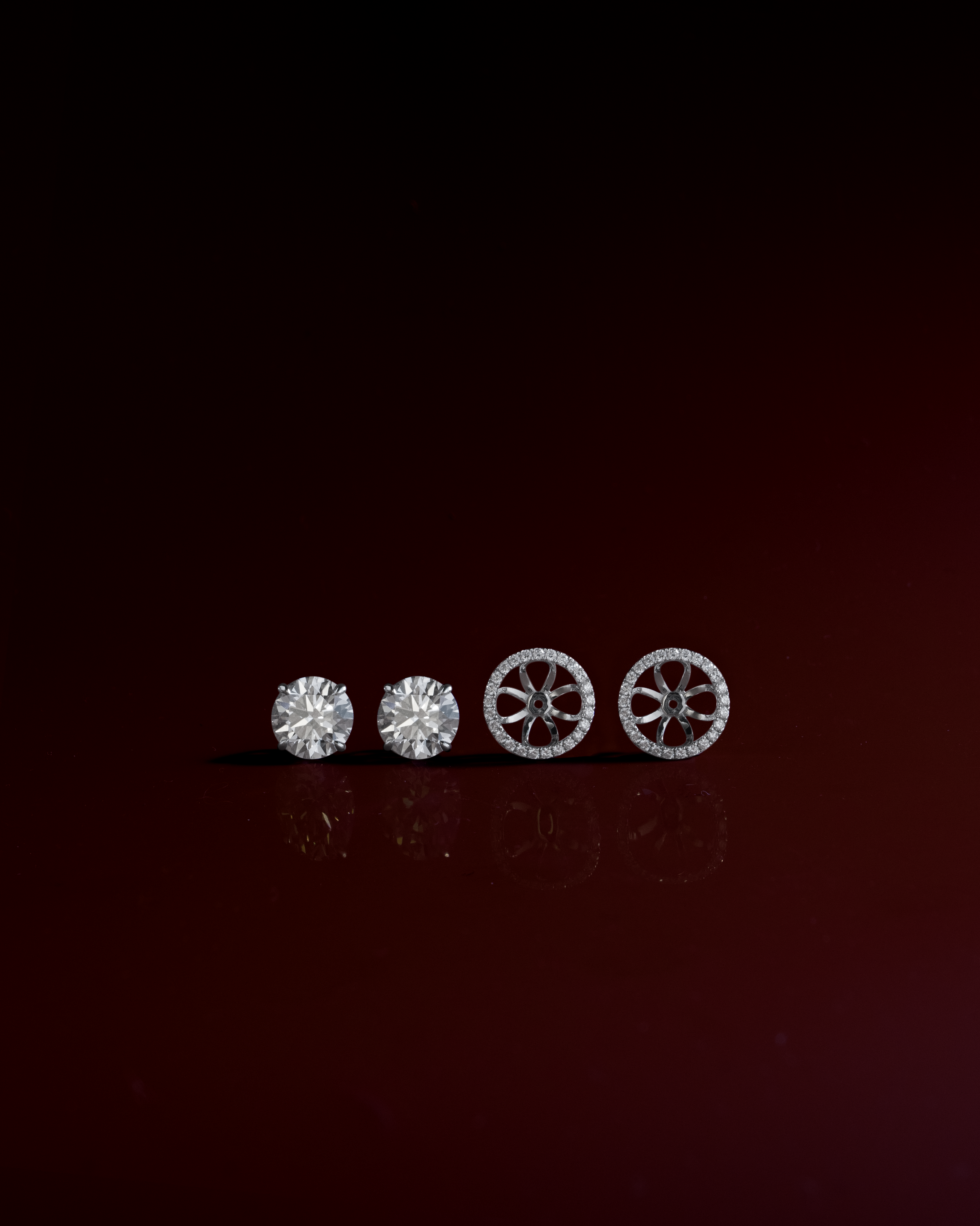 Round cut diamond stud earrings with removable halo jackets in white gold, styled on dark red – tinxx jewelry