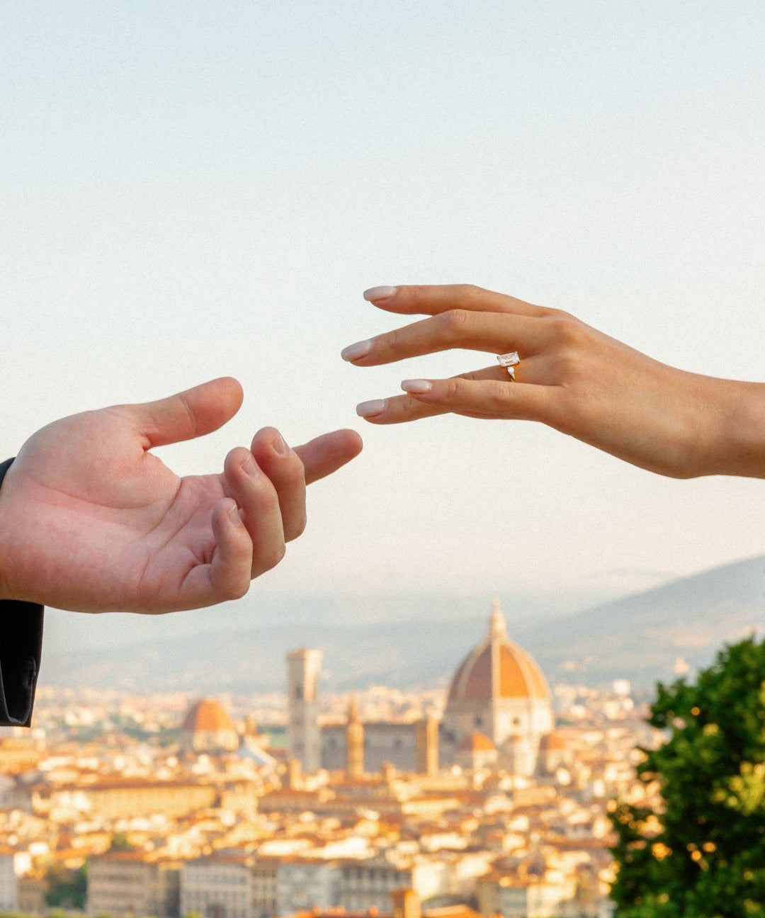 Two hands reaching towards each other with the Florence cityscape in the background