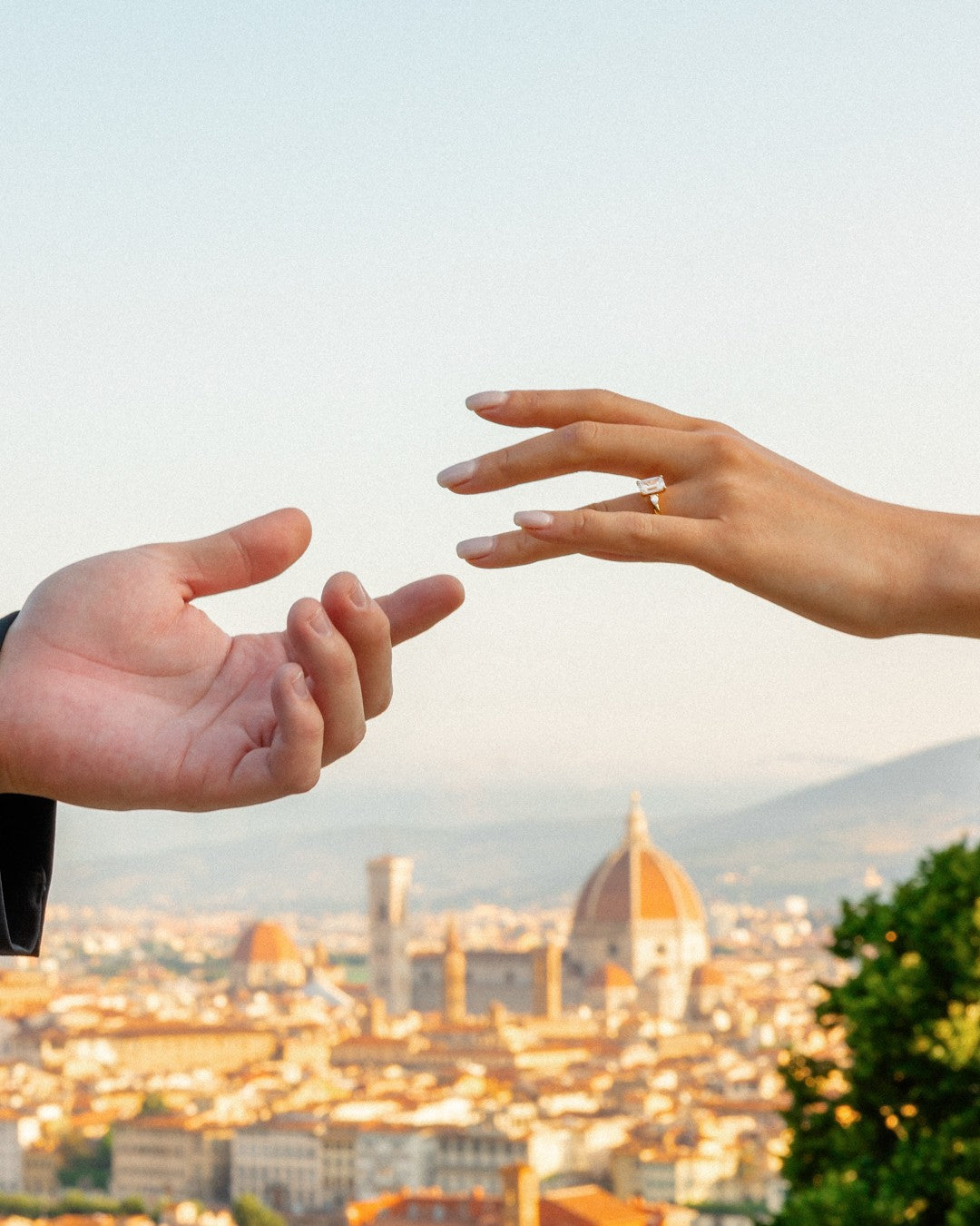 Two hands reaching towards each other with the Florence cityscape in the background