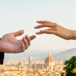 Two hands reaching towards each other with the Florence cityscape in the background
