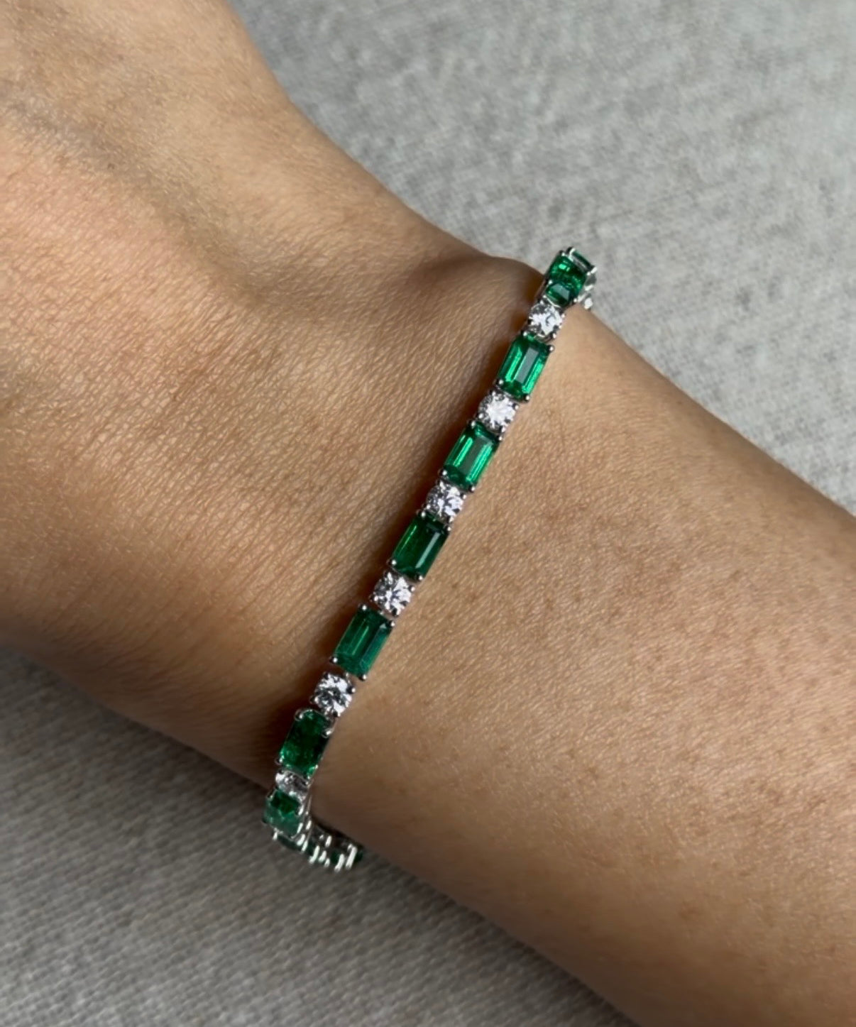 alternating zambia green emerald and round diamond bracelet on hand