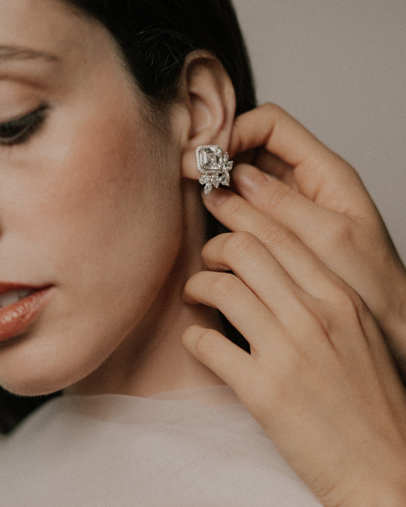 Close-up of audrey pecot wearing a tinxx asscher diamond earring with a hand adjusting it.