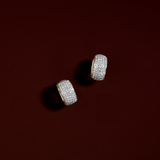 diamond huggie earrings in 18K yellow gold against red background