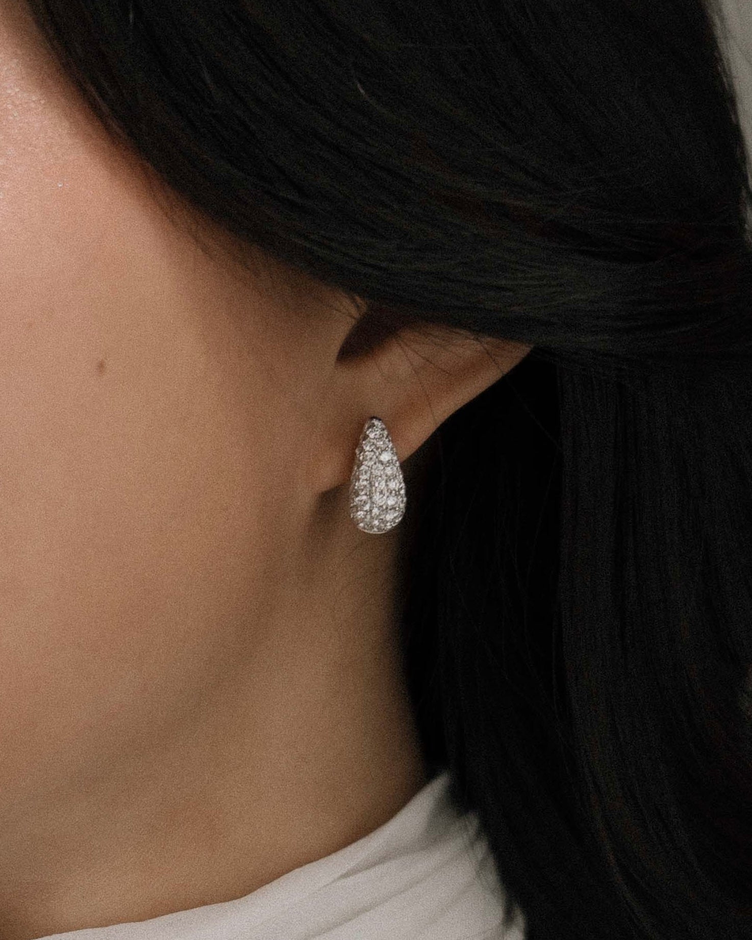 diamond teardrop earrings on ear with pavé setting in bridal styling