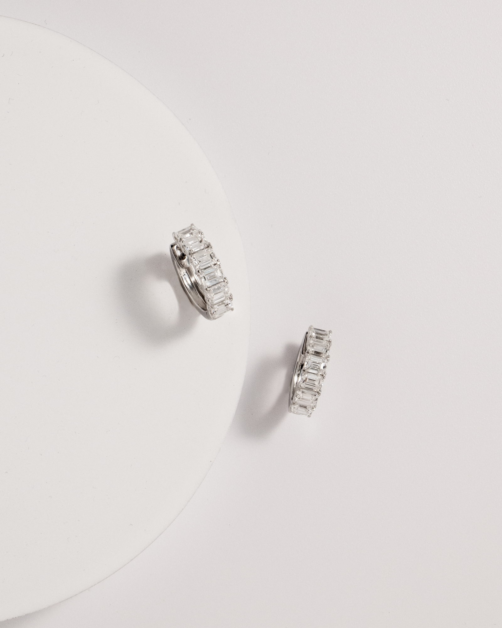 emerald diamond hoops against white background
