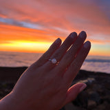Hand wearing a tinxx ring with a sunset in Hawaii