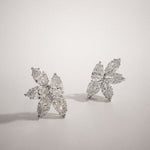 Marquise and pear cut diamond cluster stud earrings in white gold, styled at an angle