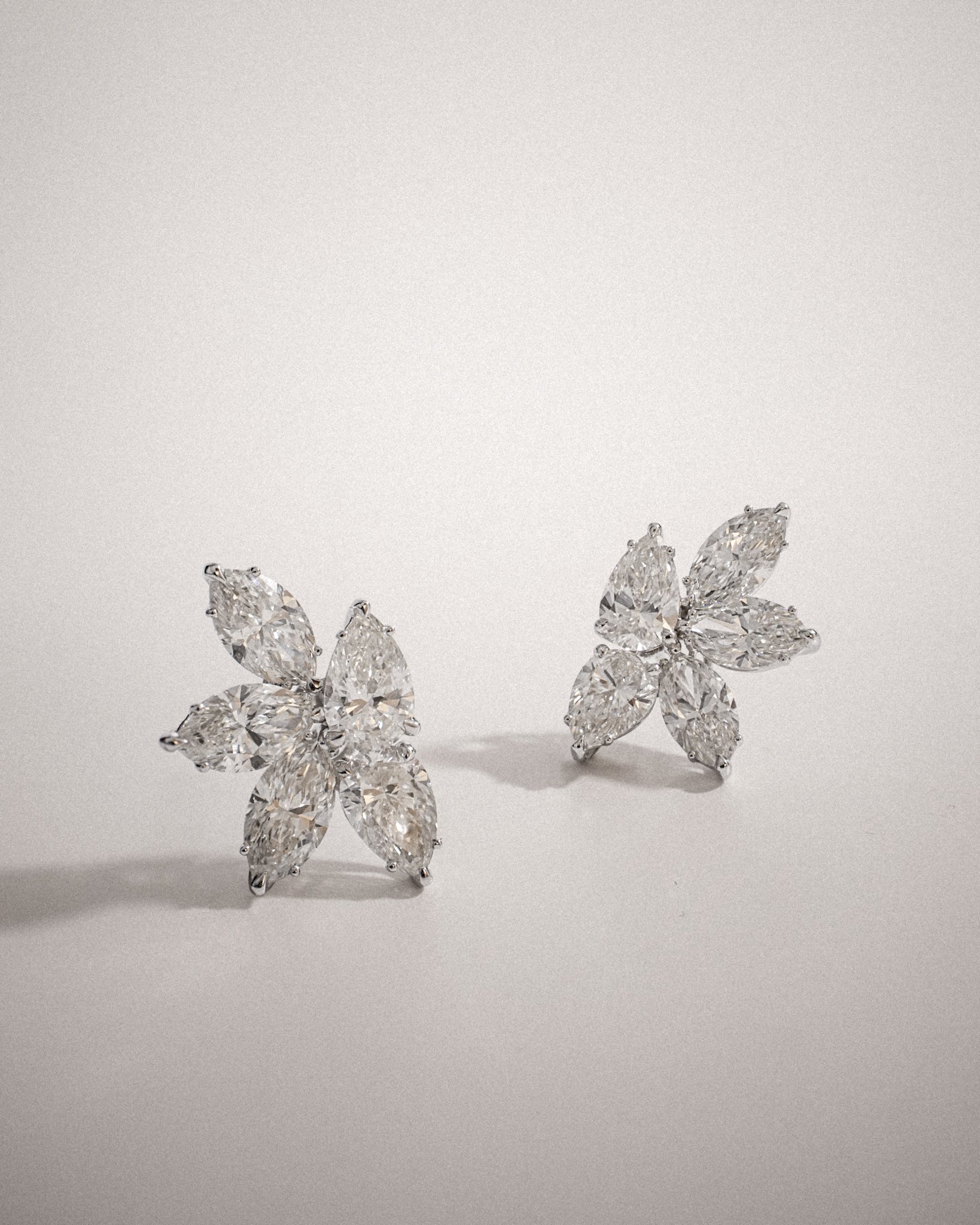Marquise and pear cut diamond cluster stud earrings in white gold, styled at an angle