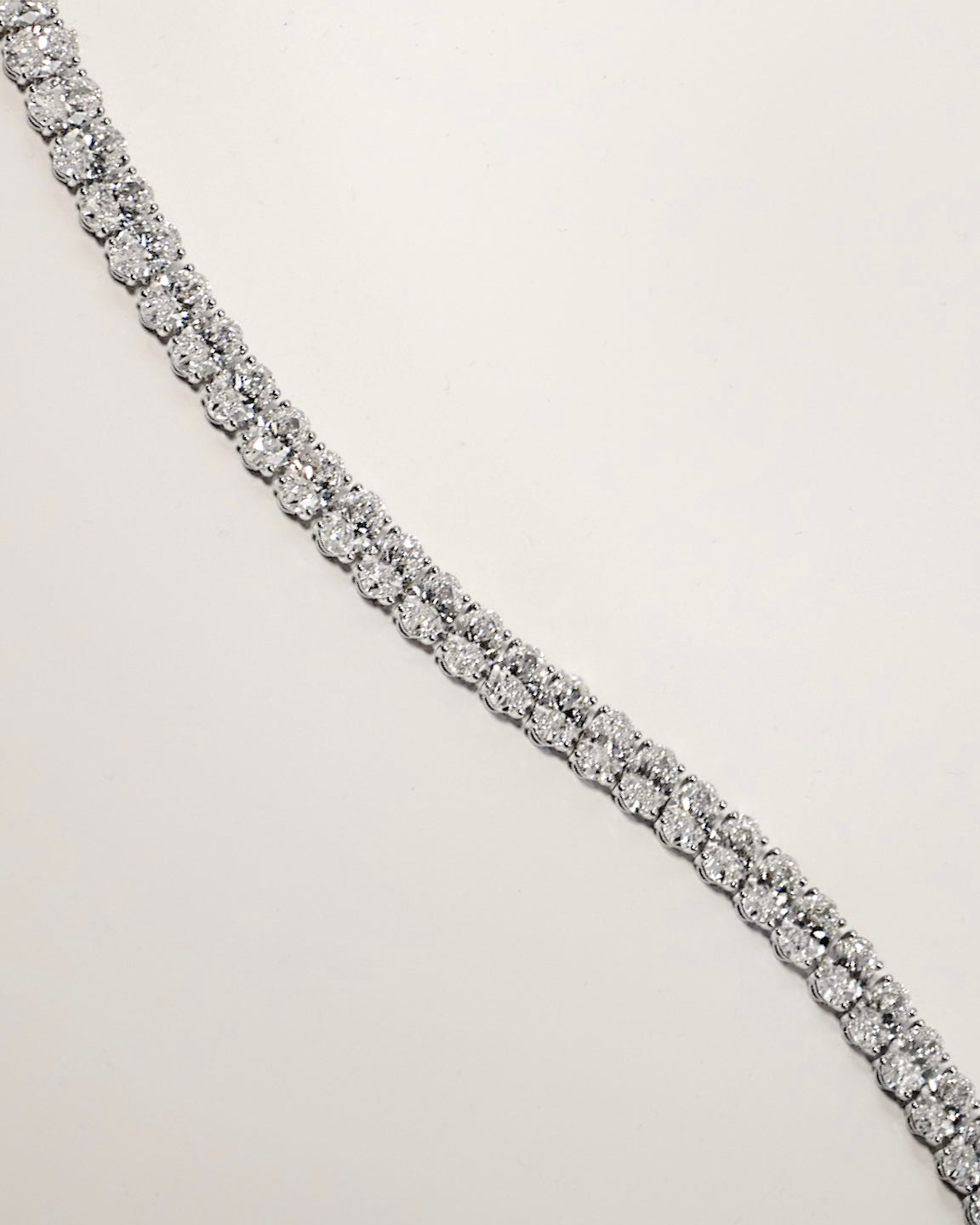 Oval cut diamond tennis bracelet in four-prong setting in white gold, close-up detail