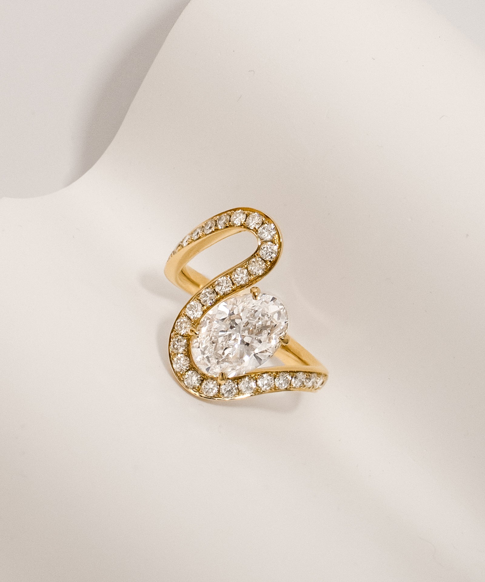 Oval cut diamond wave pavé ring in yellow gold styled on a light textured surface – tinxx jewelry