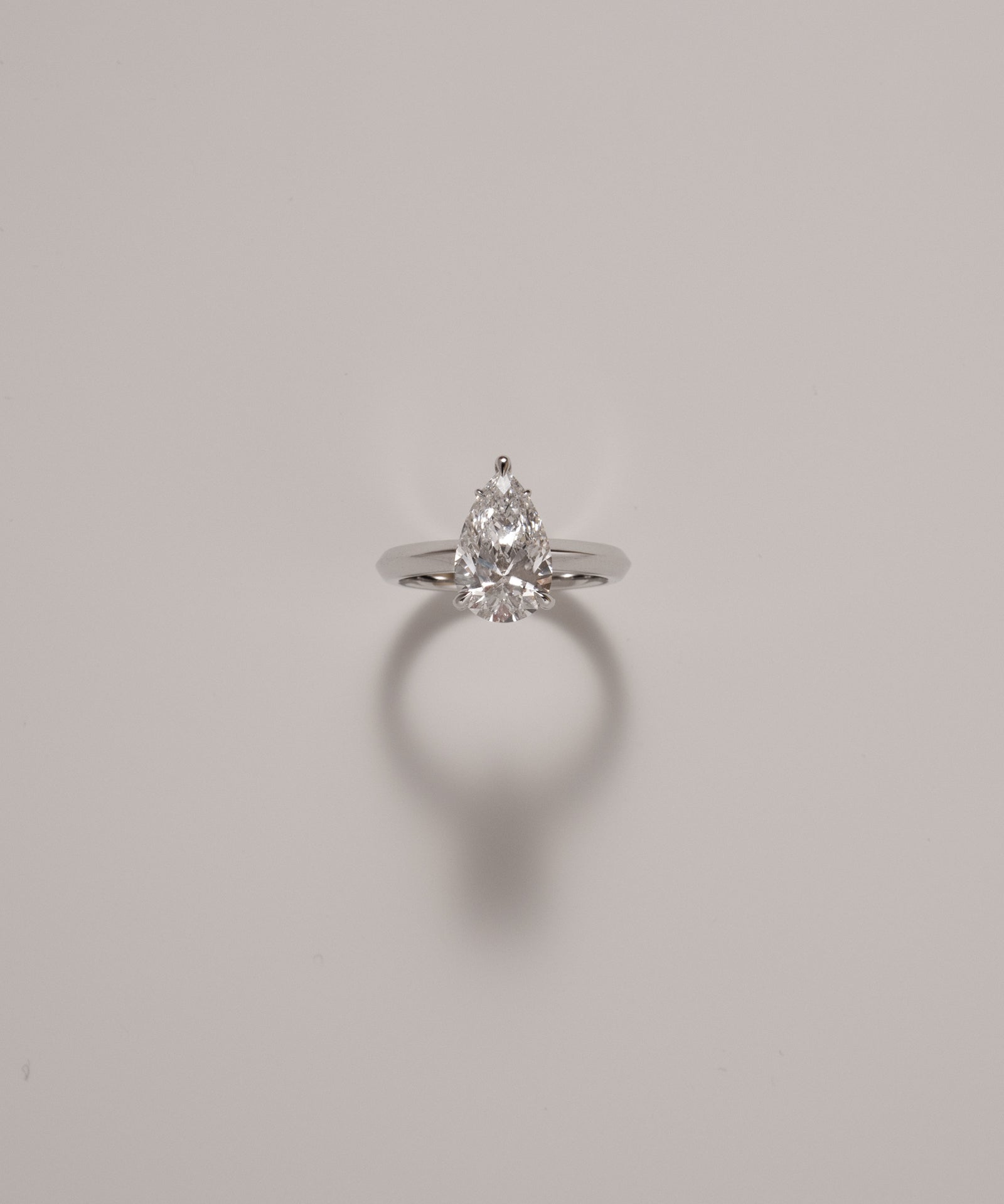 Pear cut diamond solitaire ring in knife edge setting in white gold on a soft neutral background – tinxx jewelry