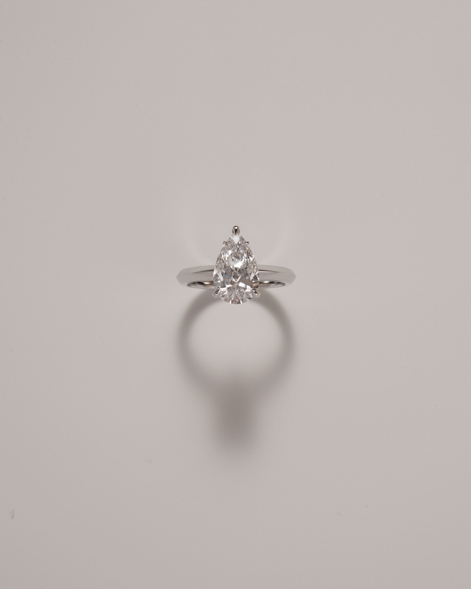 Pear cut diamond solitaire ring in knife edge setting in white gold on a soft neutral background – tinxx jewelry
