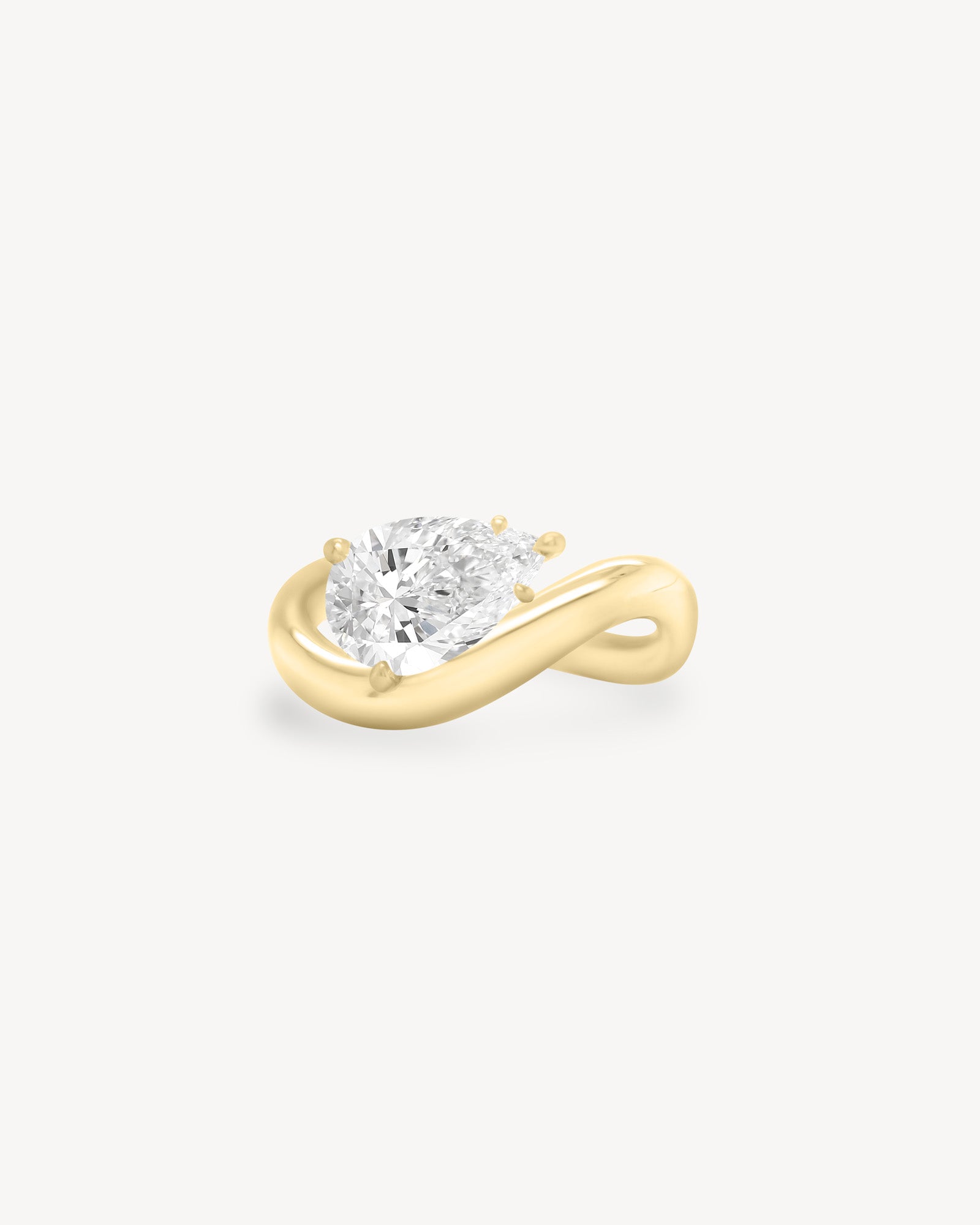 a pear diamond wave band engagement ring in 18K yellow gold set against a white background