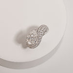 Pear cut diamond wave pavé dome ring in white gold, styled on a sculptural stand