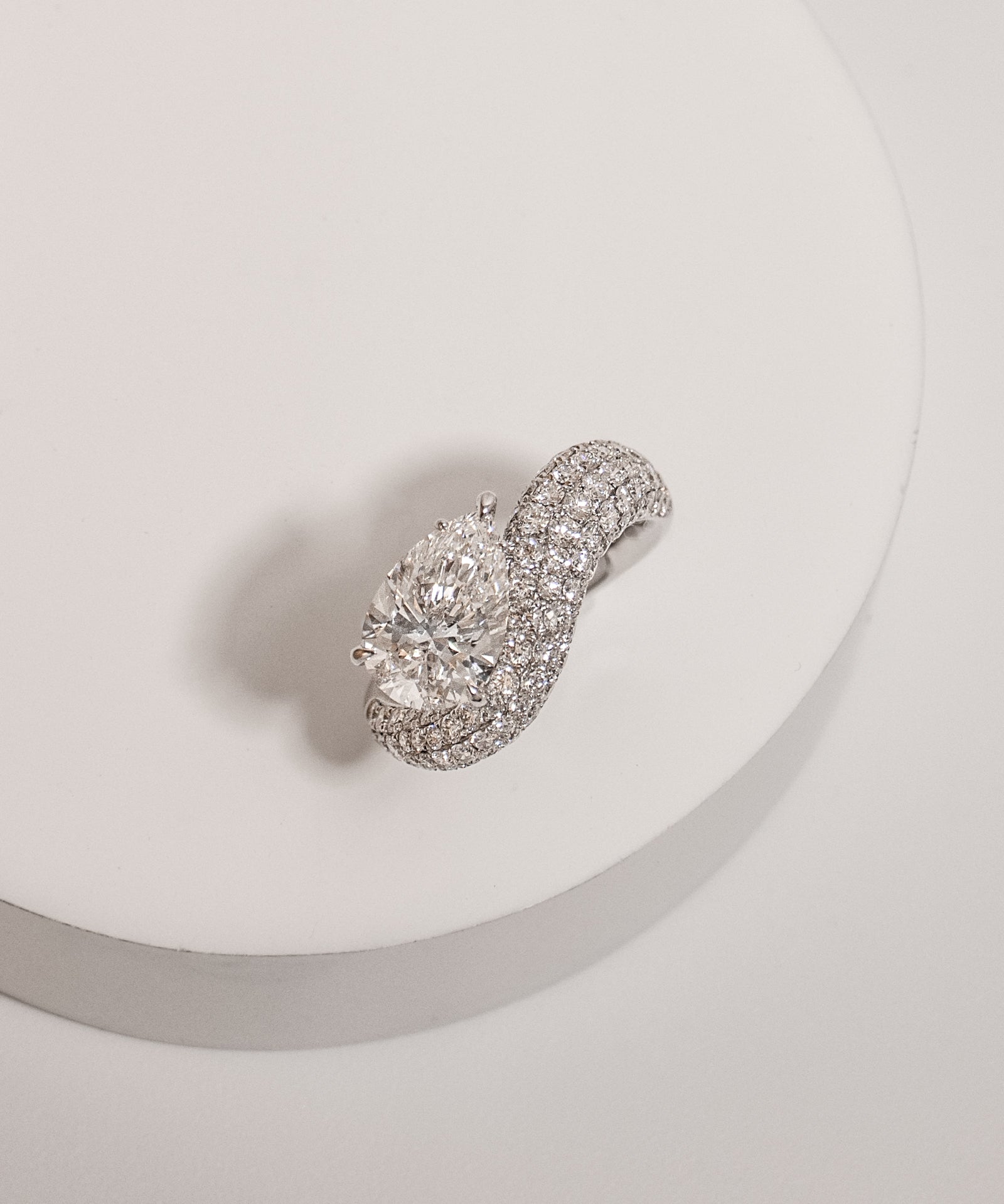 Pear cut diamond wave pavé dome ring in white gold, styled on a sculptural stand