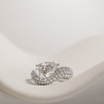 Pear cut diamond wave pavé dome ring in white gold, styled on a sculptural stand