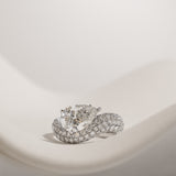 Pear cut diamond wave pavé dome ring in white gold, styled on a sculptural stand