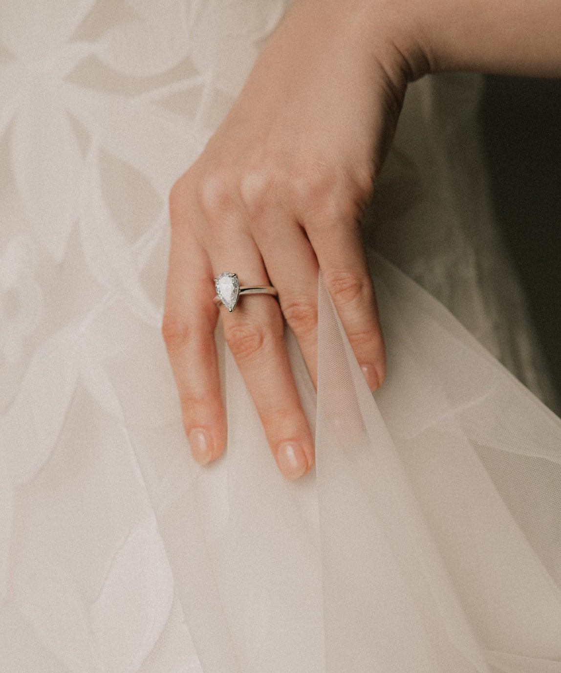 bride wearing a pear cut diamond ring in knifes edge setting 