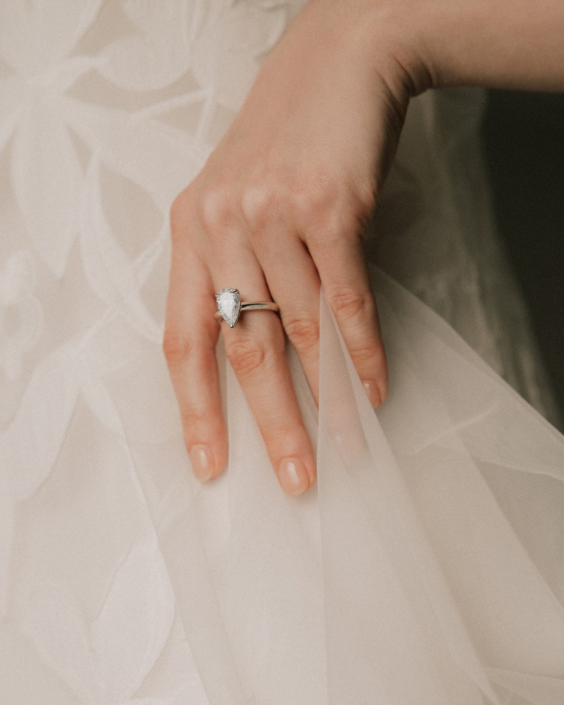 bride wearing a pear cut diamond ring in knifes edge setting 