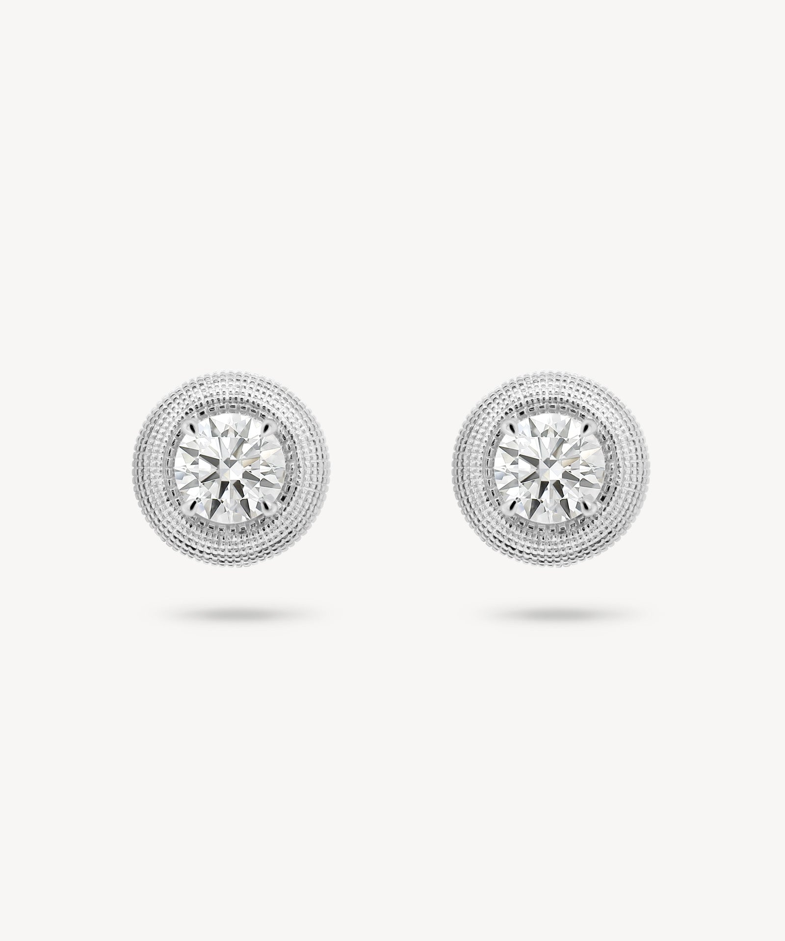 Round cut diamond stud earrings with textured gold surround in white gold