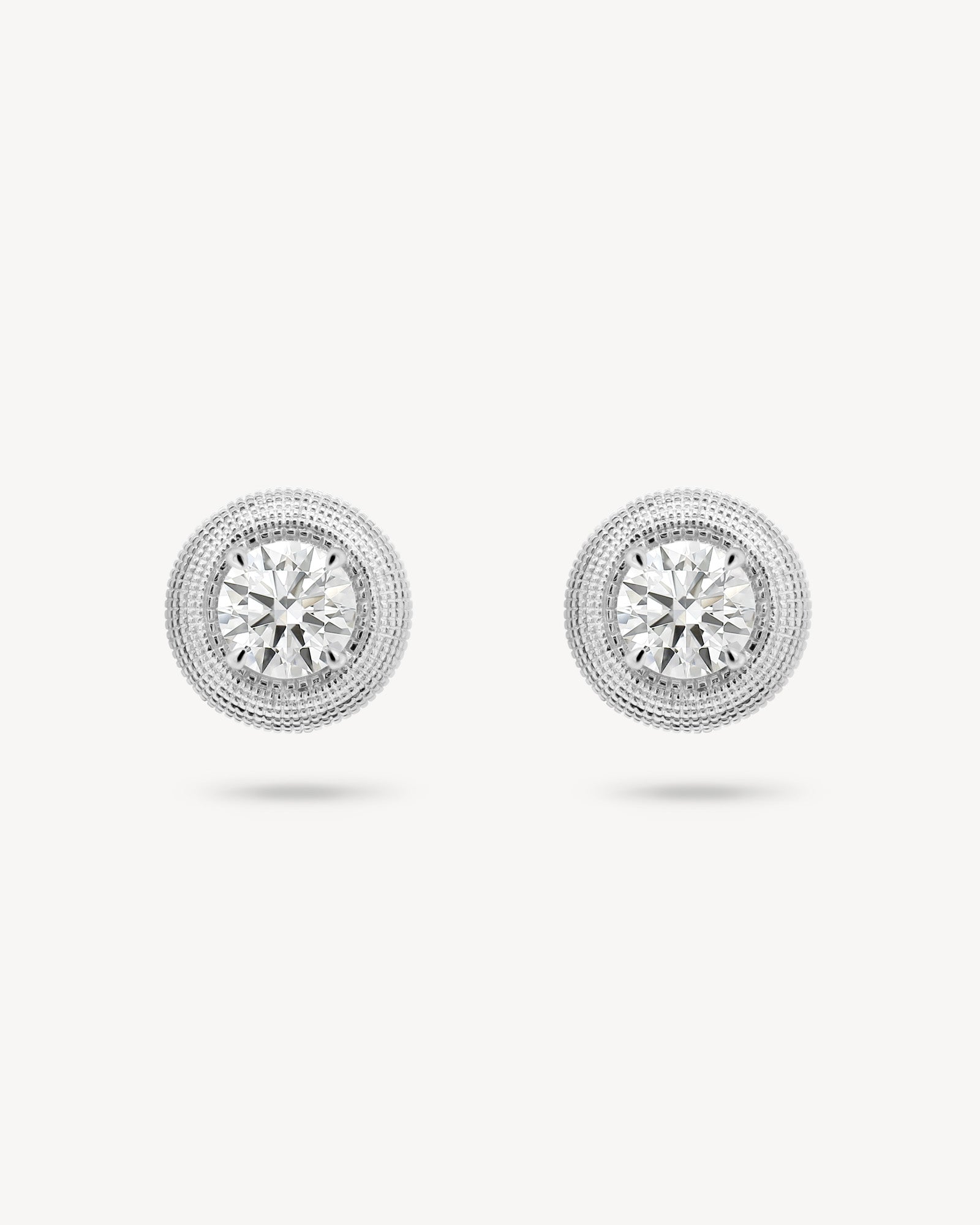 Round cut diamond stud earrings with textured gold surround in white gold