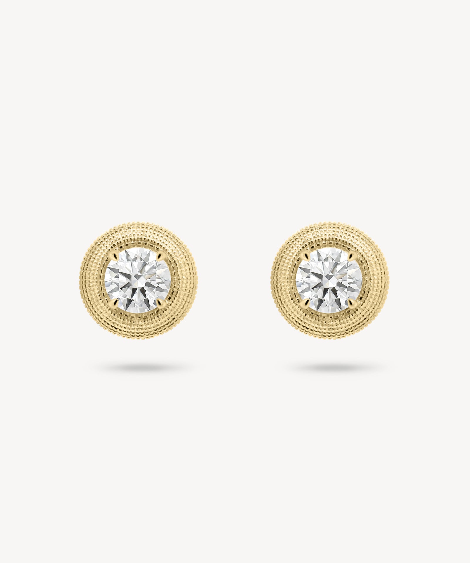 Round cut diamond stud earring with textured gold surround in yellow gold