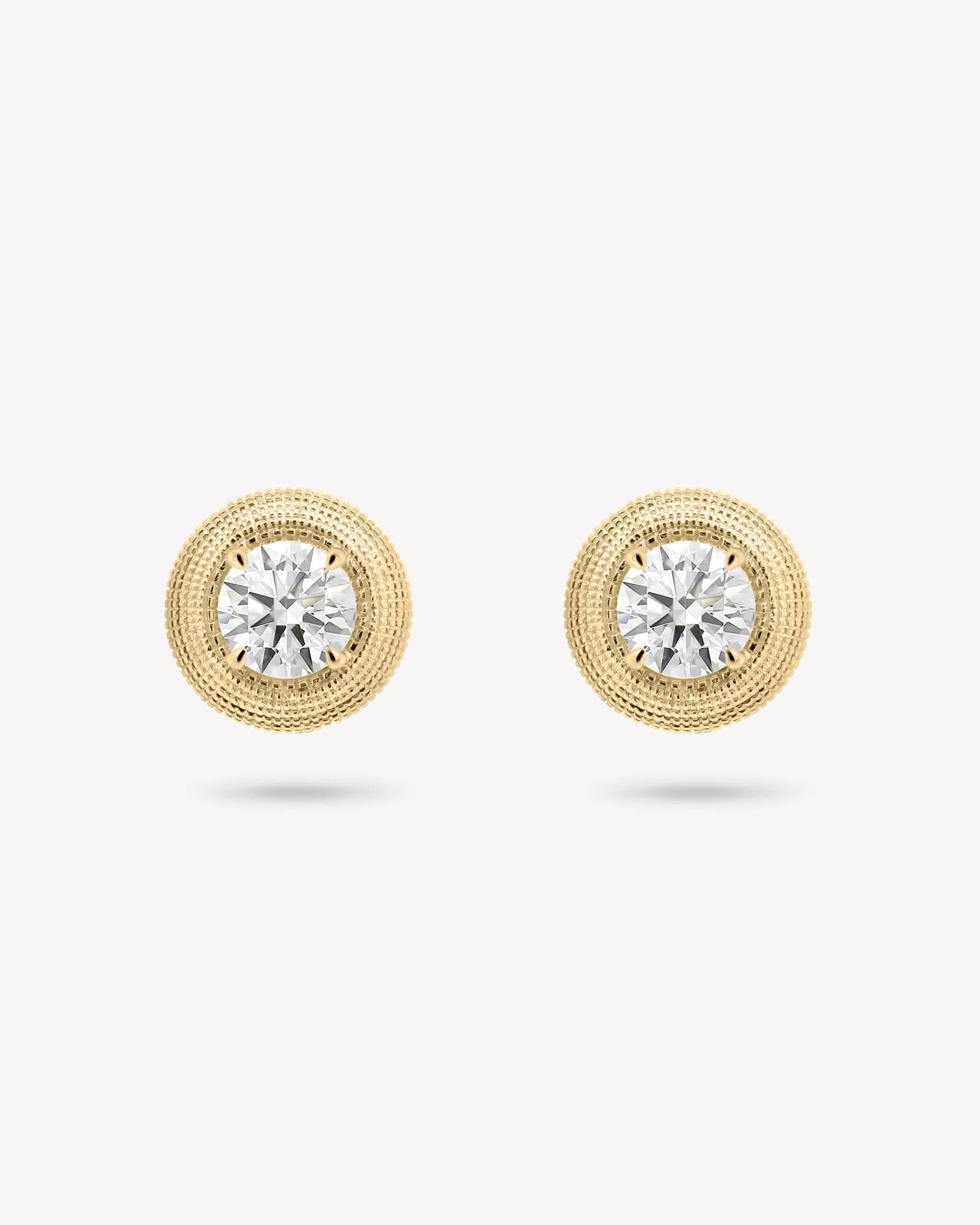 Round cut diamond stud earring with textured gold surround in yellow gold