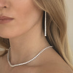 Close-up of a woman wearing a graduated long drop lab grown diamond earrings and tennis necklace in 18K white gold from tinxx.