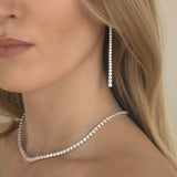 Close-up of a woman wearing a graduated long drop lab grown diamond earrings and tennis necklace in 18K white gold from tinxx.
