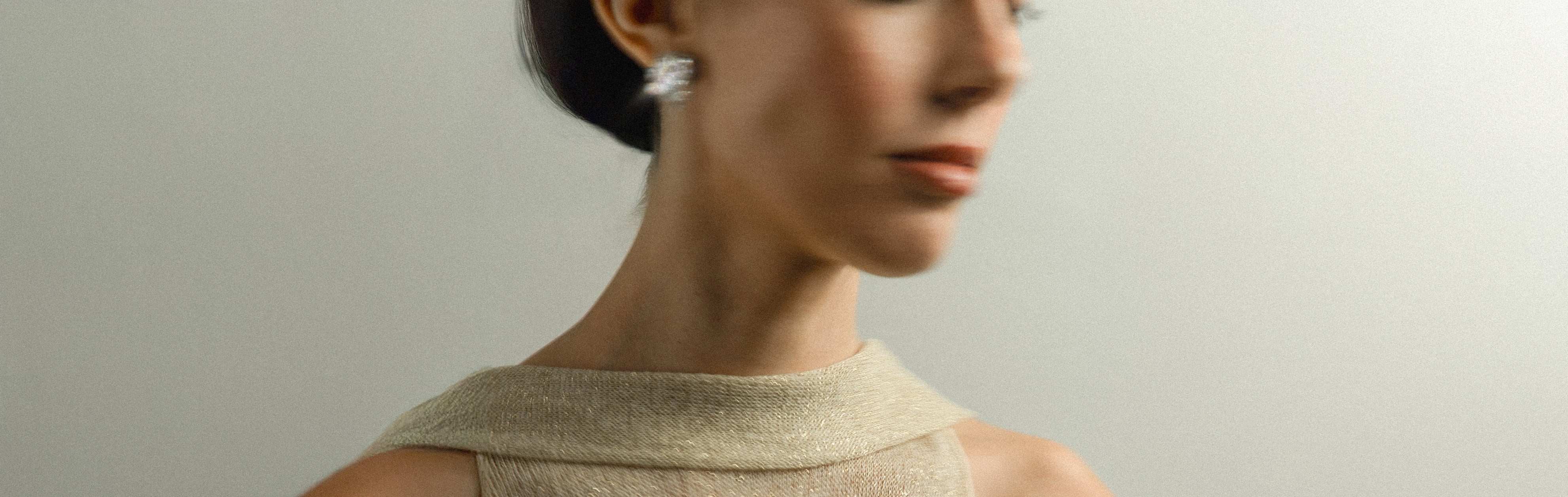 Woman wearing a beige sleeveless top with tinxx jewelry earrings