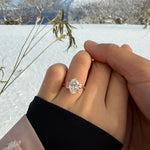 Two hands holding each other with a tinxx jewelry diamond ring against a snowy landscape.