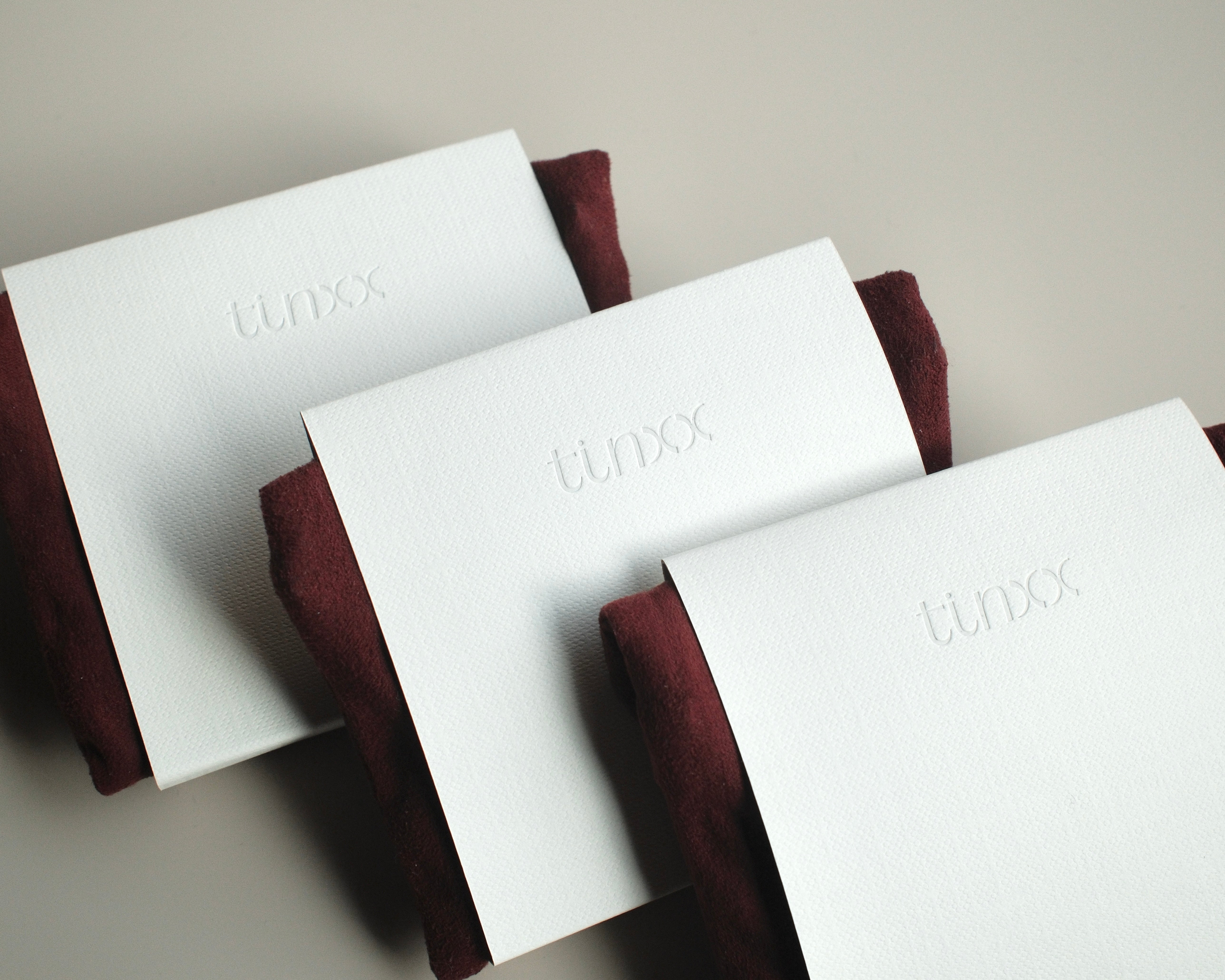 Three white packaged jewelry pouches with 'tinxx' debossed logo