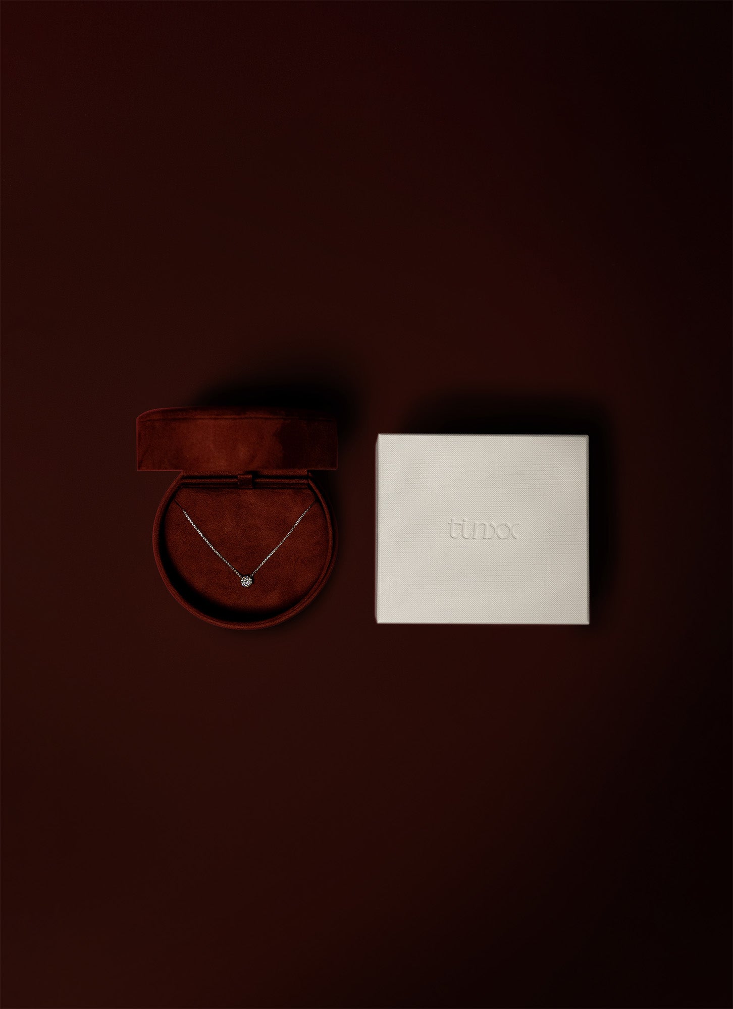 Red suede multi-purpose jewelry box with a diamond necklace and a white exterior packaging