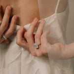 Bride adjusting her dress wearing a lab grown radiant cut diamond engagement ring from tinxx, photographed in soft neutral lighting.