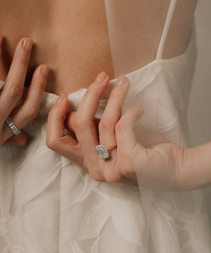 Bride adjusting her dress wearing a lab grown radiant cut diamond engagement ring from tinxx, photographed in soft neutral lighting.