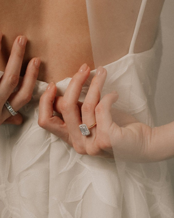 Bride adjusting her dress wearing a lab grown radiant cut diamond engagement ring from tinxx, photographed in soft neutral lighting.