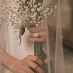 Bride holding a bouquet of flowers with a pear cut lab grown diamond halo engagement ring from tinxx