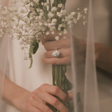 Bride holding a bouquet of flowers with a pear cut lab grown diamond halo engagement ring from tinxx