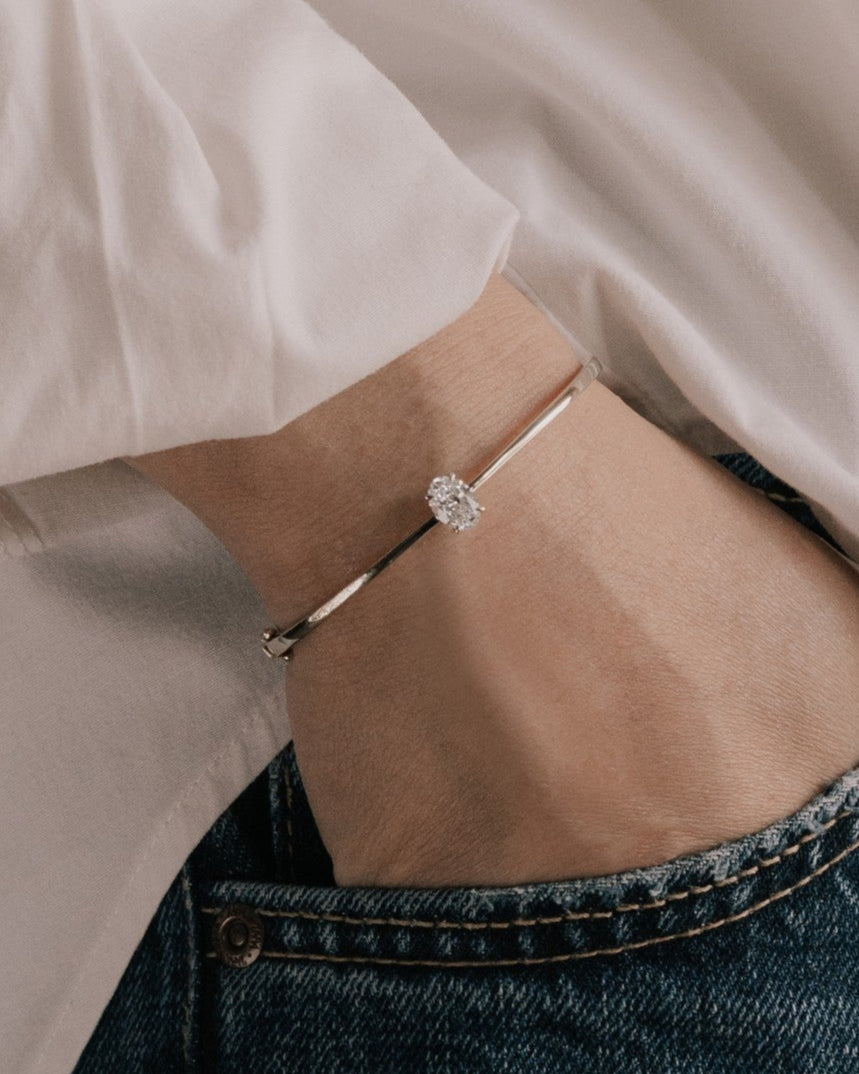 Oval cut lab grown diamond solitaire bangle in 18K yellow gold from tinxx, worn on model.