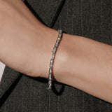 Princess cut lab grown diamond bracelet in a channel setting from tinxx, worn on wrist with a dark tailored jacket, photographed in flash.