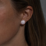 Round cut lab grown diamond stud earrings with removable halo in 18K white gold from tinxx, shown worn on ear.