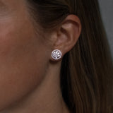 Round cut lab grown diamond stud earrings with removable halo in 18K white gold from tinxx, shown worn on ear.