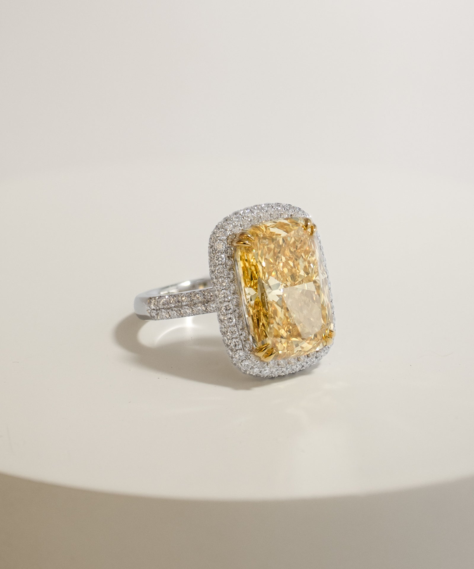 Diamond ring with a 10ct yellow diamond and a diamond halo on a light background